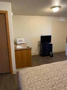 a hotel room with a bed and a microwave at Homestead Inn Extended Stay - 3 nights min in Wolf Point