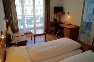 a hotel room with a bed and a desk with a computer at Hotel Victoria in Brig