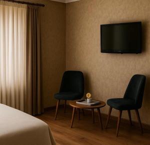 two chairs and a table in a hotel room with a tv at Red Green in İzmir