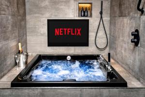 a bathroom with a bath tub with a tv on the wall at Luxury City Centre Retreat - Lux Spa Bath - Romantic in Edinburgh +17 photos