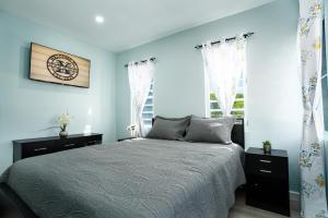 a bedroom with a bed with blue walls and windows at Xoop Homes - Zinnia #2 in Osbourn