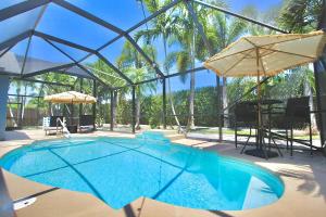 a swimming pool with two umbrellas and a table at Blue Haven Villa 3 Bedroom 2 Bathroom Home in Port Saint Lucie