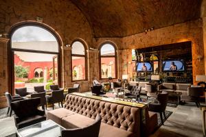 Una gran sala con un bar con sillas y televisores. en Hilton San Luis Potosi, en San Luis Potosí