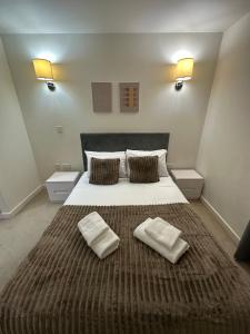 ロンドンにあるLuxury One Bedroom Flat next to Wembley Stadiumの大きなベッドとタオル2枚のある寝室