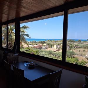a table with a view of the ocean through windows at La Foggia seaside paradise in Siculiana