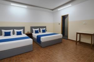 una camera d'albergo con due letti e una scrivania di In GOA Three Bedroom Penthouse with Kitchen a Candolim