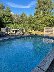a swimming pool with a table and chairs in a yard at Gatans Gård sekelskiftshus in Vesslunda