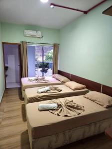 three beds in a room with a window at Pousada Monte Oliveira in Aparecida