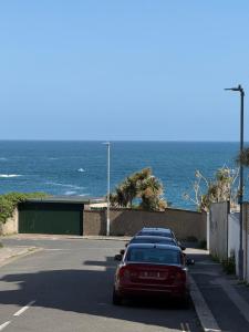 un'auto rossa parcheggiata su una strada vicino all'oceano di Seaweed Suite, secluded seaside stay with garden view a Newquay