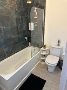 a bathroom with a bath tub and a toilet at Orchard Court Spacious 2 bedroom apartment in Wednesbury +27 photos