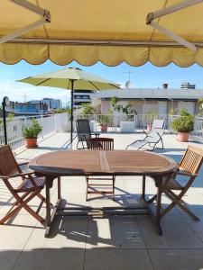 un tavolo in legno con sedie e un ombrellone su un patio di Attico Alghe Rosse Jesolo lido a Lido di Jesolo