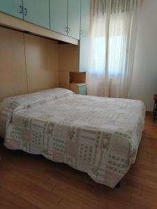 una camera da letto con un letto con una coperta sopra di Attico Alghe Rosse Jesolo lido a Lido di Jesolo