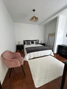 a bedroom with two beds and a pink chair at Celina Residence in Ribeira Brava
