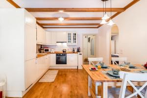 a kitchen with white cabinets and a wooden table at Giardino sul Lago - Vista su lago e montagne a Molveno in Molveno +17 photos