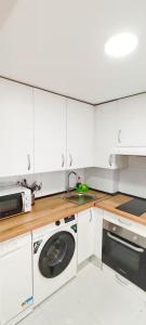 eine weiße Küche mit einer Waschmaschine und einem Waschbecken in der Unterkunft Apartamento Aeropuerto Suite 2 2 3 E in Madrid