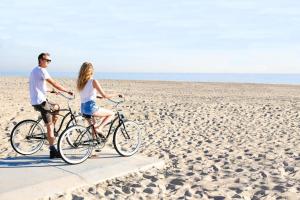 a man and woman riding bikes on the beach at 3Br Coastal Home W Large Oceanview Patio Steps To Sand By Beachview Rentals in Newport Beach