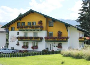 une maison jaune et blanche avec des boîtes de fleurs dans l'établissement Apartmenthaus Dornröschen, à Ramsau am Dachstein