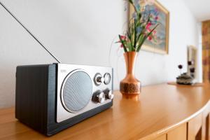 una pequeña radio sentada en una mesa con un jarrón de flores en Waldstraße 2 Windrose Kellenhusen, en Kellenhusen