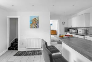 a white kitchen with two chairs and a counter at Dunallan Farm Cottage with Optional Hot Tub & Stunning Views in Island of Bute