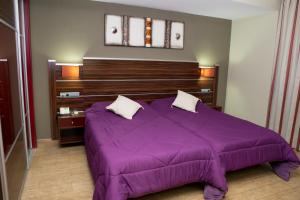 a bedroom with a purple bed with a wooden headboard at Hotel Noguera El Albir in Albir