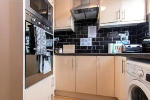 a kitchen with a stove and a washer and dryer at Portobello Rooms by PrimeCityHosts in London
