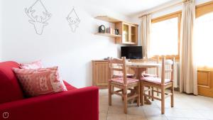 sala de estar con sofá rojo, mesa y sillas en Mulino 5, en Valdisotto