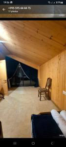 a room with a wooden ceiling with a chair and blue curtains at kotej lazi in Itʼkhvisi