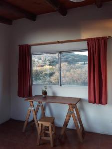 a table and stool in front of a window at Departamento Los Horneritos in La Cumbre