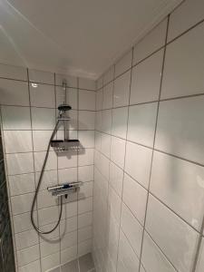 a shower in a white tiled bathroom with a hose at Ski in-ski out leilighet Hemsedal in Fausko +25 photos