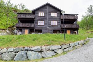 a black house on a hill with a stone wall at Ski in-ski out leilighet Hemsedal in Fausko