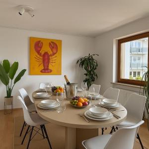 マルクドルフにあるSTAYS Gehrenberg am Bodenseeの白い椅子とフルーツのボウルが置かれたダイニングテーブル