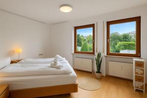 マルクドルフにあるSTAYS Gehrenberg am Bodenseeの白いベッドルーム(ベッド1台、窓2つ付) +4枚の写真
