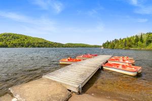 a group of boats tied to a dock on a lake at Le P'tit Bonheur - Plage avec embarcations in Sainte-Lucie-de-Doncaster