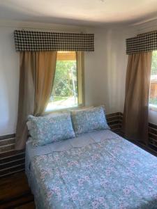 a bedroom with a bed and two windows at Chale Beija flor in Praia Grande