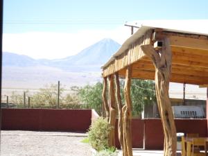 een houten gebouw met een berg op de achtergrond bij Hostal Mirador in San Pedro de Atacama