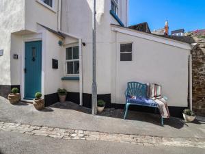 une chaise bleue assise devant une maison dans l'établissement Honeymoon Cottage, à Bideford