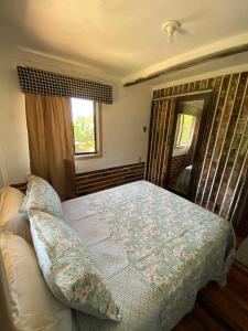 a bedroom with a bed and a window at Chale Beija flor in Praia Grande +8 photos