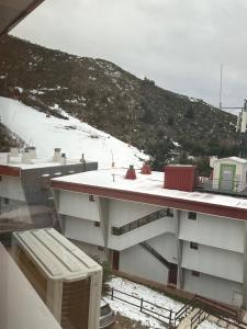 a view of a building with a snow covered mountain at Aral in La Pinilla +3 photos