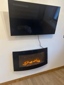 a tv hanging on a wall with a fireplace at Aral in La Pinilla