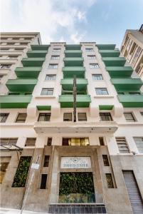 a tall white building with green windows at Daher Center Hotel in São Paulo