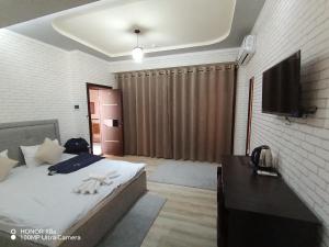 a bedroom with a bed and a flat screen tv at Milano Garden Plaza Samarkand in Samarkand