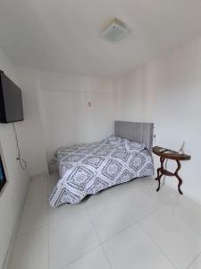 a white bedroom with a bed and a table at Comfortable apartment in Aracaju in Aracaju