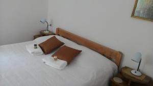 a bedroom with a bed with white sheets and brown pillows at Apartments Prisnac in Pakoštane