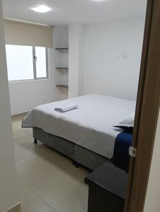 ein Schlafzimmer mit einem Bett in einem Zimmer mit einem Fenster in der Unterkunft Posada Los Geranios in Duitama