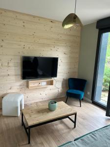 a living room with a flat screen tv on a wooden wall at Refuge nature de Aumontzey in Granges-Aumontzey