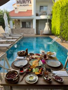 una bandeja de comida en una mesa frente a una piscina en NURİYE ALACATI, en Alacati