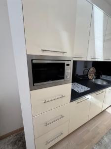 Una cocina con gabinetes blancos y un microondas. en Apartman Dvor 92 m2, Marijin Dvor, en Sarajevo