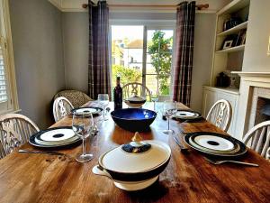 a wooden table with plates and wine glasses on it at Prospect Cottage in Hythe