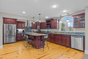 a kitchen with wooden cabinets and a island with bar stools at Shell Hill house Waterfront, kayaks, grill, pier in Sealevel