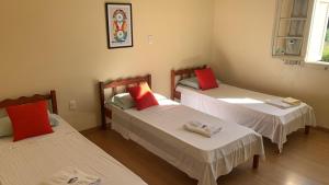 a room with three beds with red pillows at Hotel Murialdo in Caxias do Sul